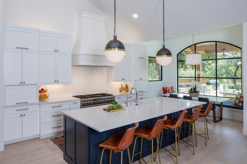 Eat-in kitchen - large transitional u-shaped light wood floor and beige floor eat-in kitchen idea in Austin with a farmhouse sink, recessed-panel cabinets, white cabinets, quartzite countertops, white backsplash, ceramic backsplash, paneled appliances, an island and white countertops