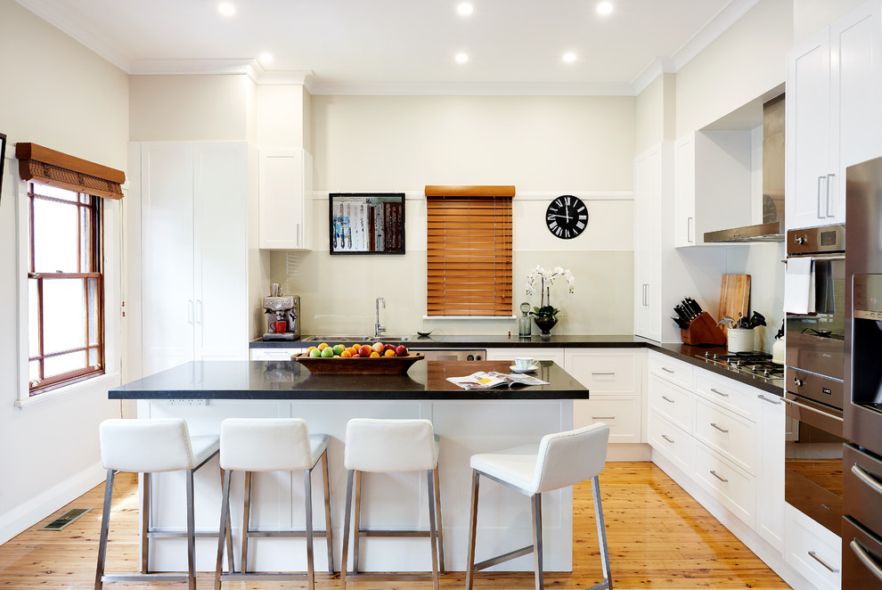 Offene, Mittelgroße Moderne Küche in L-Form mit Doppelwaschbecken, flächenbündigen Schrankfronten, weißen Schränken, Küchengeräten aus Edelstahl, hellem Holzboden und Kücheninsel in Sydney
