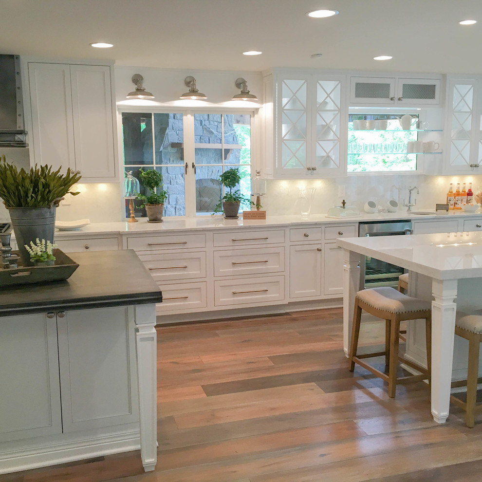 Inspiration for a huge transitional l-shaped light wood floor and brown floor kitchen remodel in Other with a farmhouse sink, beaded inset cabinets, white cabinets, zinc countertops, white backsplash, marble backsplash, stainless steel appliances and two islands