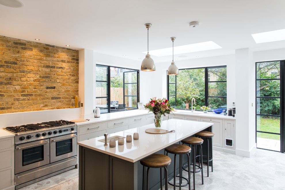 This is an example of a large contemporary l-shaped kitchen/diner in London with an integrated sink, shaker cabinets, grey cabinets, composite countertops, terrazzo flooring, an island and stainless steel appliances.