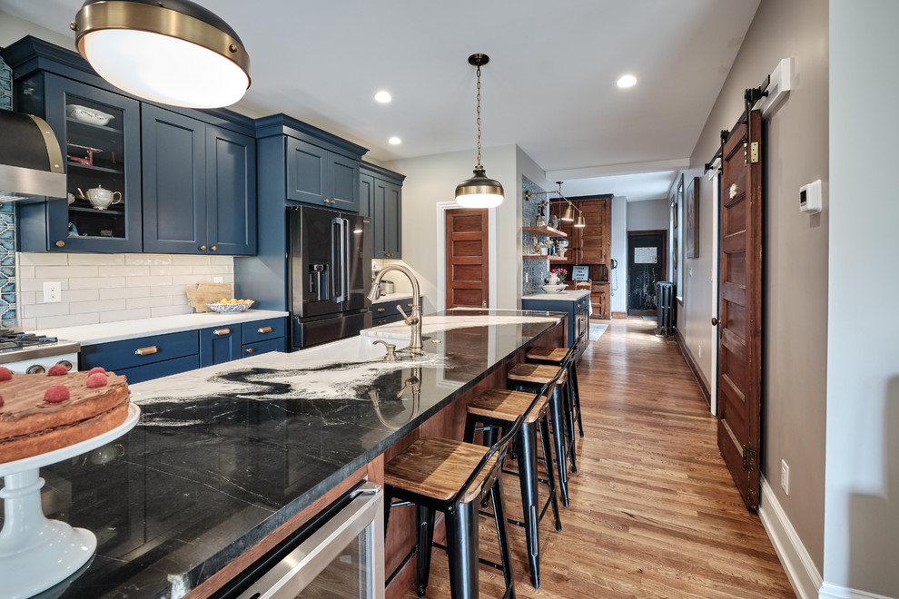 フィラデルフィアにあるラグジュアリーな広いエクレクティックスタイルのおしゃれなキッチン (エプロンフロントシンク、落し込みパネル扉のキャビネット、青いキャビネット、珪岩カウンター、グレーのキッチンパネル、セラミックタイルのキッチンパネル、黒い調理設備、無垢フローリング、茶色い床、マルチカラーのキッチンカウンター) の写真
