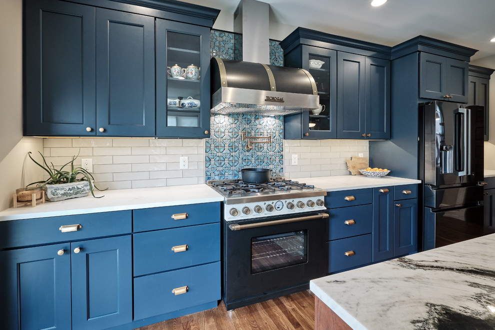 Inspiration for a large eclectic galley medium tone wood floor and brown floor open concept kitchen remodel in Philadelphia with a farmhouse sink, recessed-panel cabinets, blue cabinets, quartzite countertops, gray backsplash, ceramic backsplash, black appliances, an island and multicolored countertops