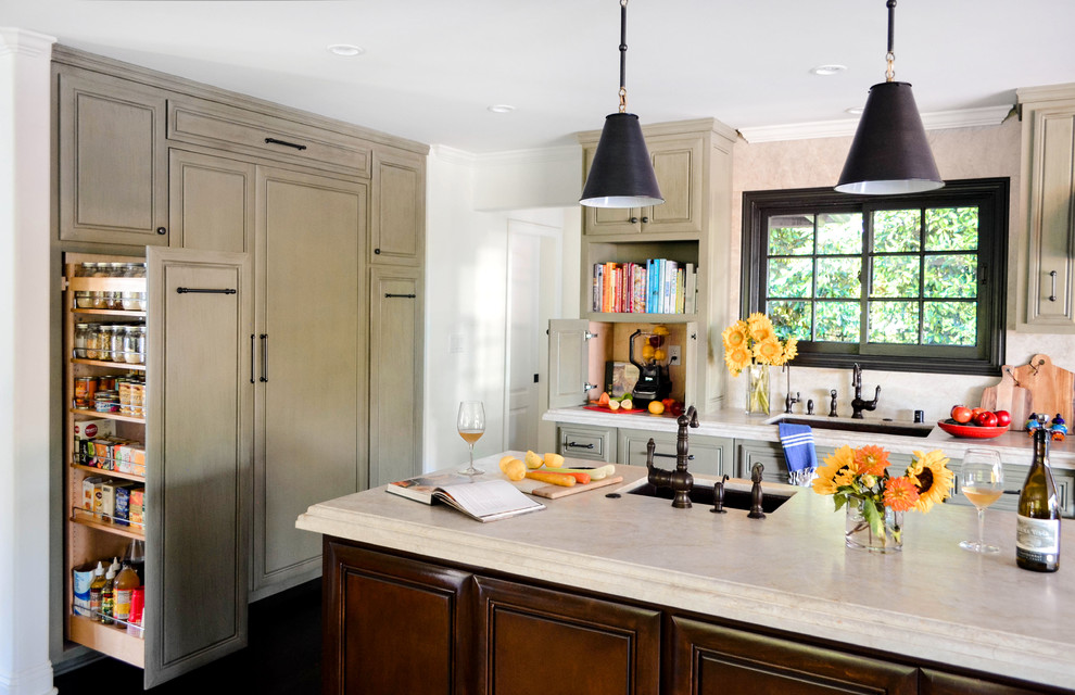 Example of a large tuscan l-shaped dark wood floor and brown floor open concept kitchen design in Los Angeles with an undermount sink, raised-panel cabinets, green cabinets, quartzite countertops, beige backsplash, stone slab backsplash, paneled appliances, an island and beige countertops