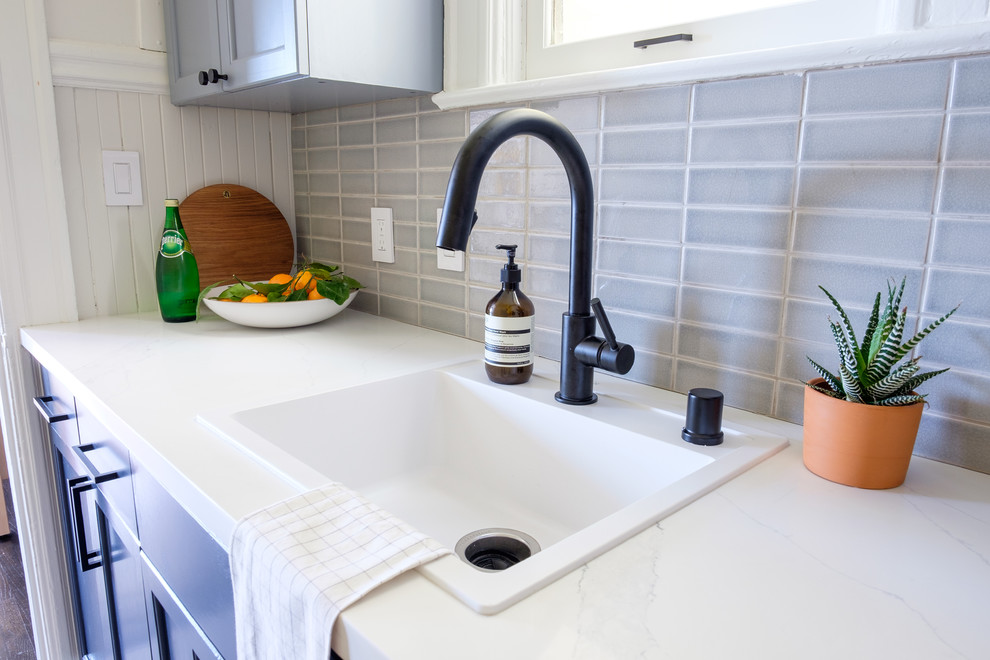 Modern inredning av ett litet vit linjärt vitt kök och matrum, med en undermonterad diskho, skåp i shakerstil, blå skåp, bänkskiva i kvarts, grått stänkskydd, stänkskydd i keramik, rostfria vitvaror, klinkergolv i keramik och grått golv