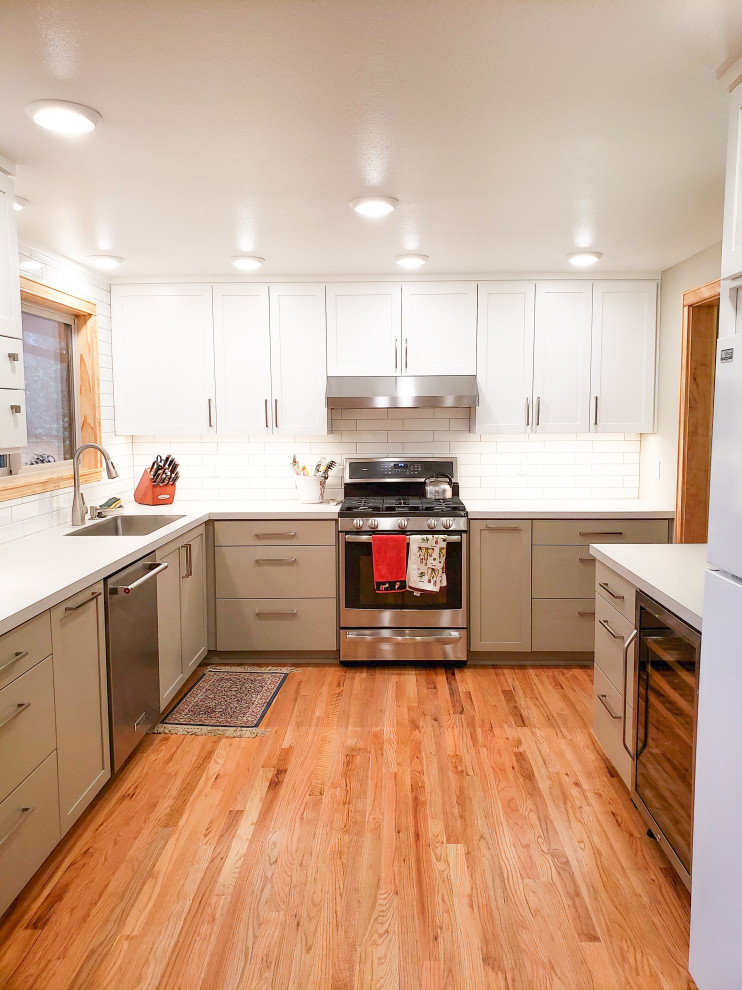 Exempel på ett mellanstort modernt vit vitt kök, med en undermonterad diskho, skåp i shakerstil, vita skåp, laminatbänkskiva, vitt stänkskydd, stänkskydd i tunnelbanekakel, rostfria vitvaror, mellanmörkt trägolv och en köksö