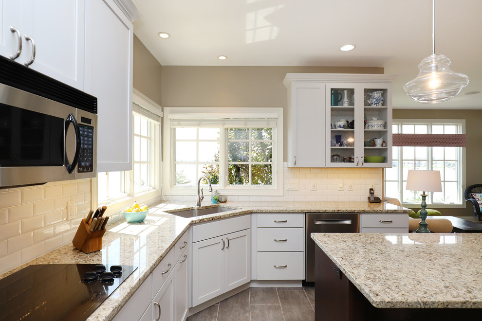 Eat-in kitchen - mid-sized traditional u-shaped ceramic tile and brown floor eat-in kitchen idea in Grand Rapids with an undermount sink, recessed-panel cabinets, white cabinets, granite countertops, white backsplash, subway tile backsplash, stainless steel appliances and an island