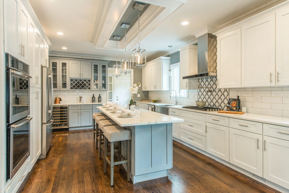 Photo of a modern u-shaped kitchen in New York with a belfast sink, shaker cabinets, white cabinets and an island.