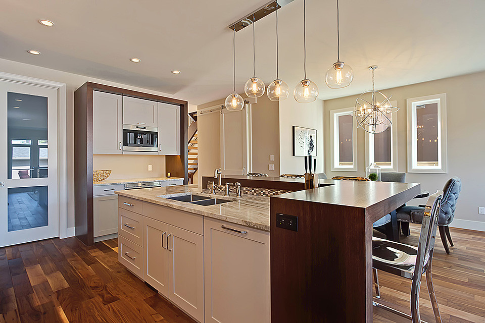 Medium sized contemporary l-shaped open plan kitchen in Calgary with a submerged sink, shaker cabinets, white cabinets, wood worktops, beige splashback, mosaic tiled splashback, stainless steel appliances, dark hardwood flooring, an island and brown floors.