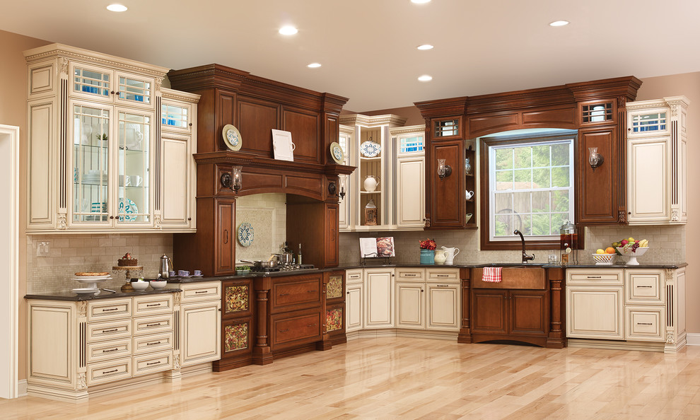 Example of a large classic l-shaped light wood floor kitchen design in New York with a farmhouse sink, raised-panel cabinets, brown cabinets, quartzite countertops, beige backsplash, ceramic backsplash, paneled appliances and an island