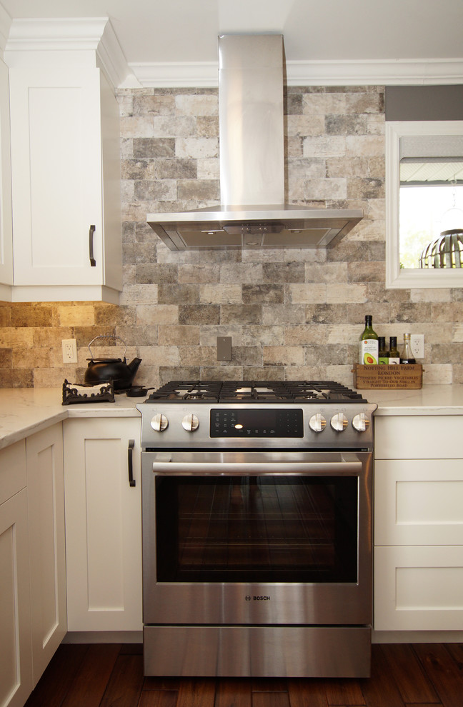 Idéer för mellanstora rustika vitt kök, med en undermonterad diskho, luckor med infälld panel, vita skåp, bänkskiva i kvartsit, flerfärgad stänkskydd, stänkskydd i skiffer, rostfria vitvaror, mellanmörkt trägolv, en köksö och brunt golv