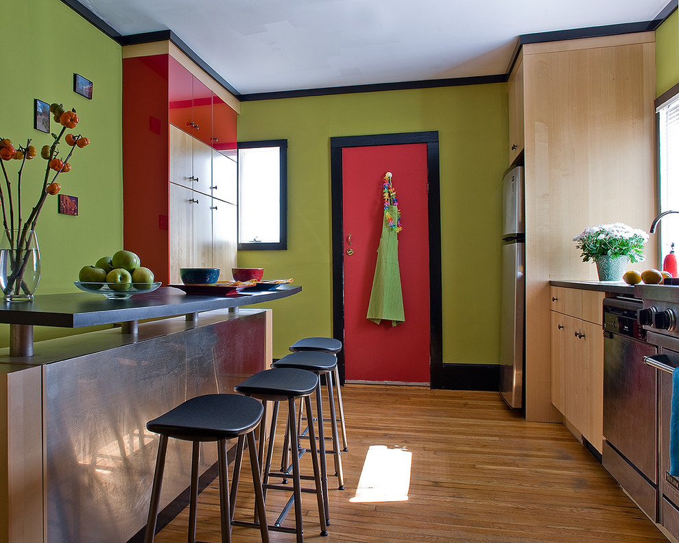 Exemple d'une arrière-cuisine parallèle moderne en bois clair de taille moyenne avec un évier posé, un placard à porte plane, un plan de travail en stratifié, une crédence rouge, un électroménager en acier inoxydable, un sol en bois brun et îlot.