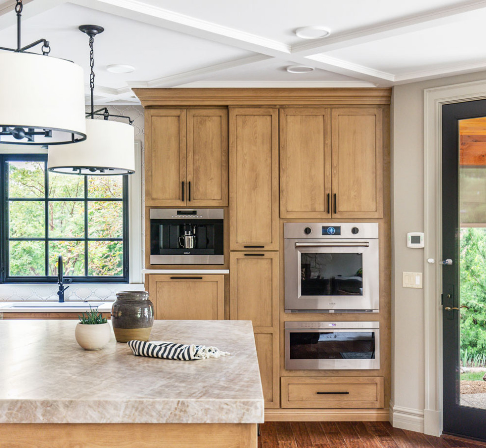 Bild på ett mellanstort funkis grå grått kök, med en undermonterad diskho, släta luckor, skåp i ljust trä, bänkskiva i kvartsit, beige stänkskydd, stänkskydd i keramik, rostfria vitvaror, mellanmörkt trägolv, en köksö och brunt golv