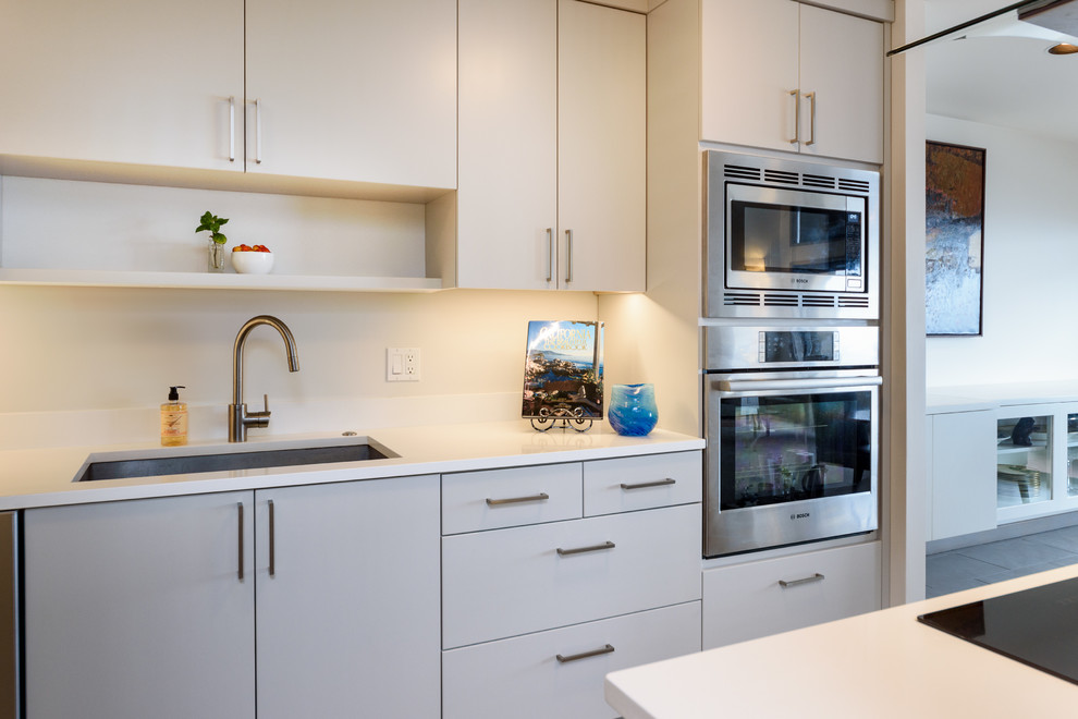 Design ideas for a small modern galley open plan kitchen in Seattle with a submerged sink, flat-panel cabinets, grey cabinets, quartz worktops, white splashback, stainless steel appliances, porcelain flooring, an island and white floors.