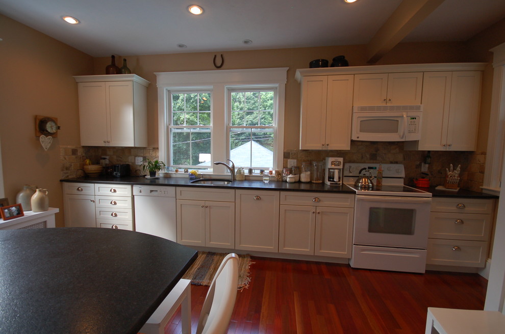 Example of a small classic single-wall medium tone wood floor eat-in kitchen design in Boston with an undermount sink, shaker cabinets, white cabinets, multicolored backsplash, stone tile backsplash, white appliances, granite countertops and an island