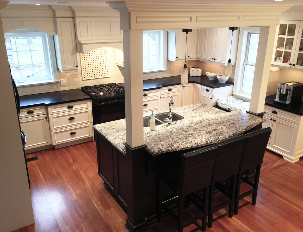 Example of a mid-sized minimalist u-shaped medium tone wood floor eat-in kitchen design in Toronto with a double-bowl sink, beaded inset cabinets, light wood cabinets, beige backsplash, subway tile backsplash, black appliances and an island