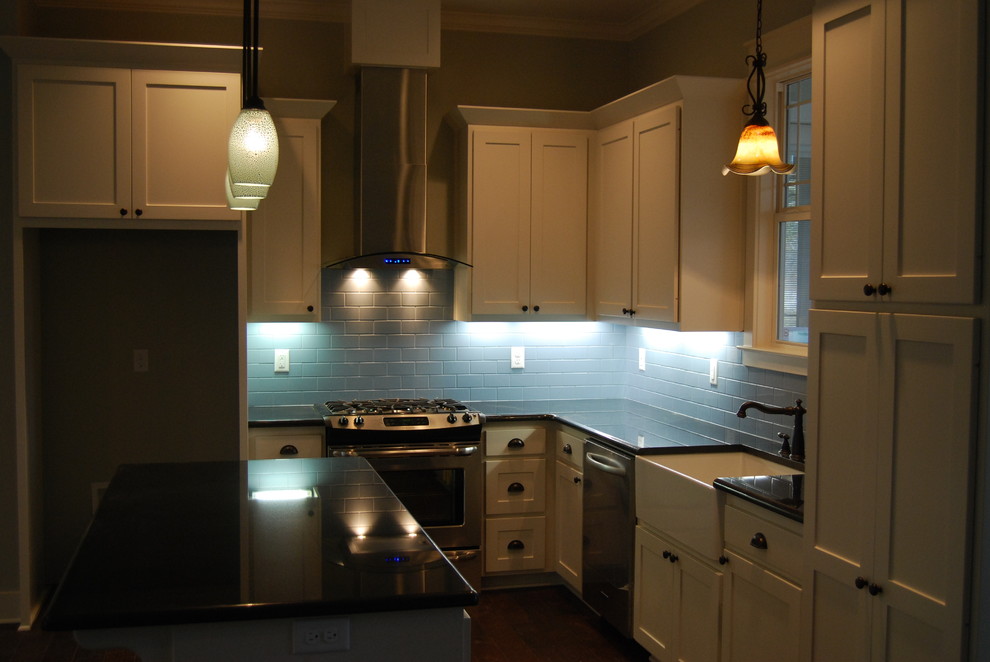 Foto på ett litet amerikanskt kök, med en rustik diskho, skåp i shakerstil, vita skåp, granitbänkskiva, blått stänkskydd, stänkskydd i cementkakel, rostfria vitvaror, mellanmörkt trägolv och en köksö