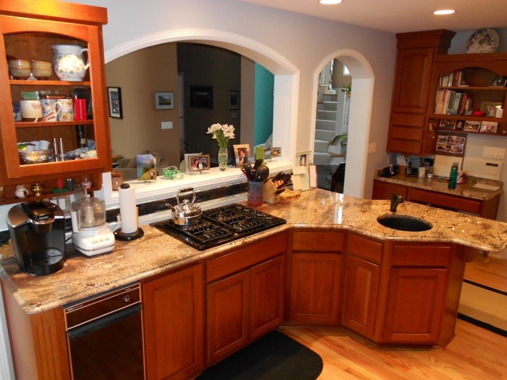 Пример оригинального дизайна: отдельная, параллельная кухня в классическом стиле с врезной мойкой, фасадами с выступающей филенкой, темными деревянными фасадами, гранитной столешницей, разноцветным фартуком и черной техникой