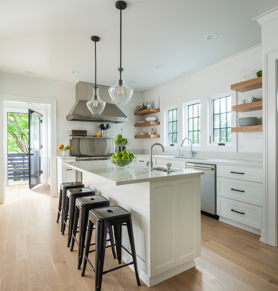 Example of a mid-sized transitional u-shaped light wood floor and beige floor open concept kitchen design in Seattle with an undermount sink, shaker cabinets, white cabinets, metallic backsplash, stainless steel appliances, an island and quartzite countertops