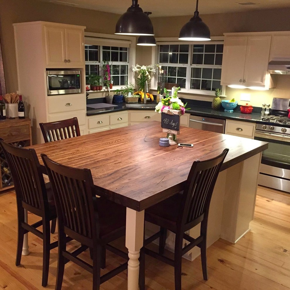 Foto di una grande cucina minimal con top in legno, paraspruzzi nero, elettrodomestici in acciaio inossidabile e parquet chiaro