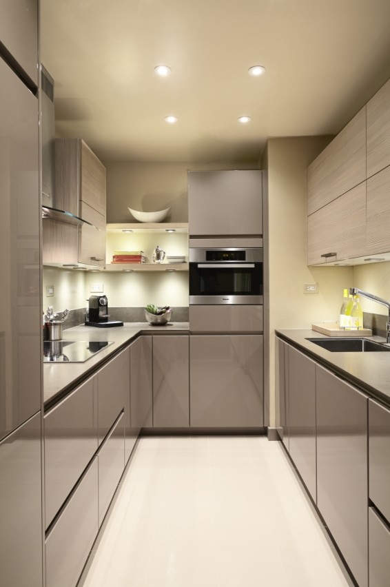 Inspiration for a small modern u-shaped enclosed kitchen in New York with flat-panel cabinets, light wood cabinets, grey splashback, stainless steel appliances, no island, beige floors and grey worktops.