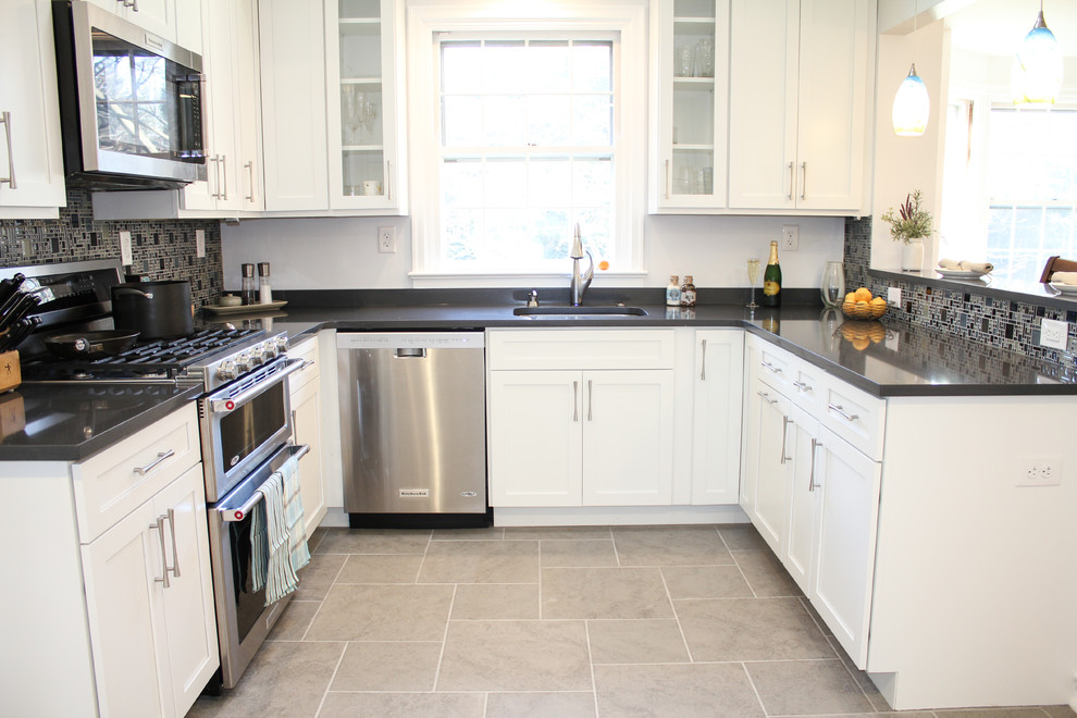 Photo of a small traditional u-shaped kitchen in Philadelphia with a submerged sink, shaker cabinets, white cabinets, quartz worktops, green splashback, glass tiled splashback, stainless steel appliances, ceramic flooring and a breakfast bar.