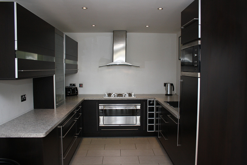 Свежая идея для дизайна: п-образная кухня-гостиная среднего размера в стиле модернизм с черными фасадами - отличное фото интерьера