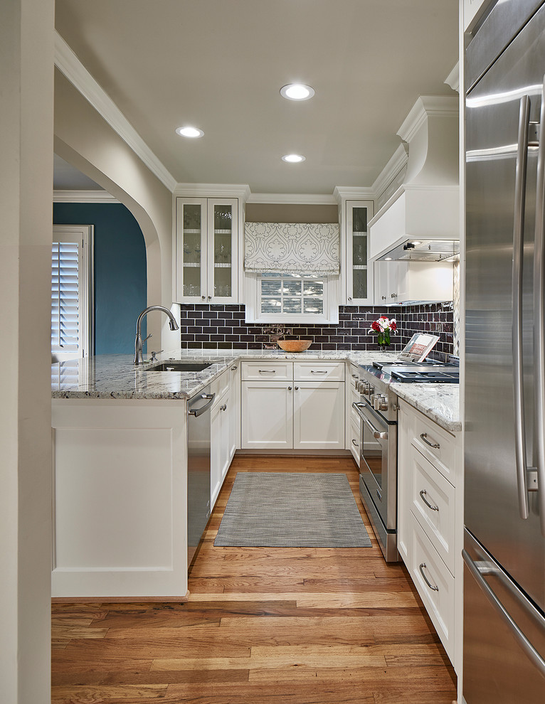 Small transitional u-shaped medium tone wood floor and brown floor eat-in kitchen photo in Dallas with an undermount sink, white cabinets, granite countertops, brown backsplash, ceramic backsplash, stainless steel appliances, a peninsula, shaker cabinets and gray countertops