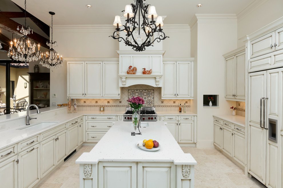 Bild på ett stort vintage u-kök, med en undermonterad diskho, luckor med upphöjd panel, vita skåp, vitt stänkskydd, rostfria vitvaror, en köksö, marmorbänkskiva, stänkskydd i keramik och marmorgolv