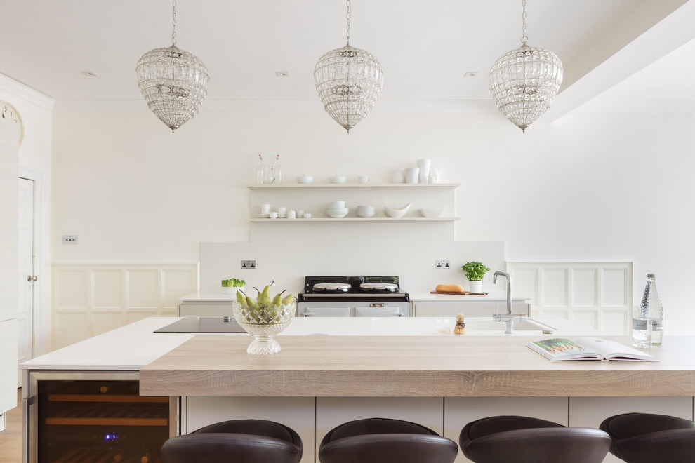 Inspiration for a transitional l-shaped kitchen remodel in Hertfordshire with white backsplash, white appliances and an island