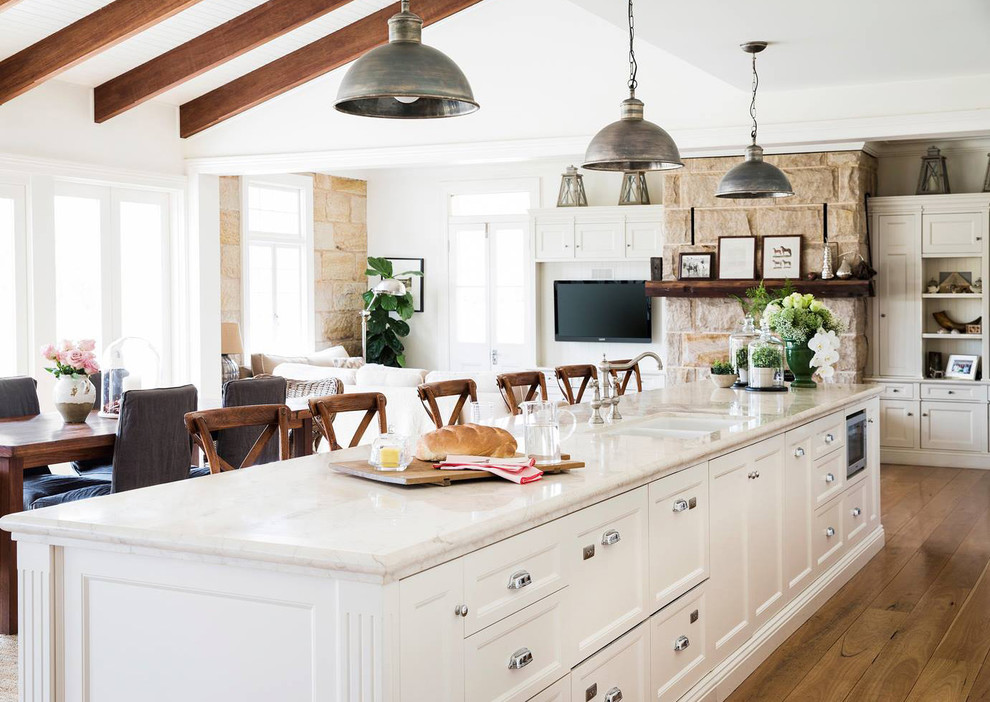 Foto de cocina de estilo de casa de campo abierta con fregadero de doble seno, armarios con paneles empotrados, puertas de armario blancas, suelo de madera en tonos medios y una isla