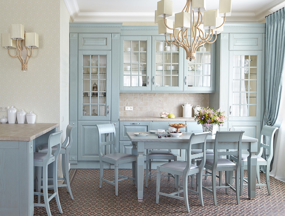 На фото: угловая кухня в классическом стиле с обеденным столом, фасадами с выступающей филенкой, синими фасадами, бежевым фартуком и полуостровом