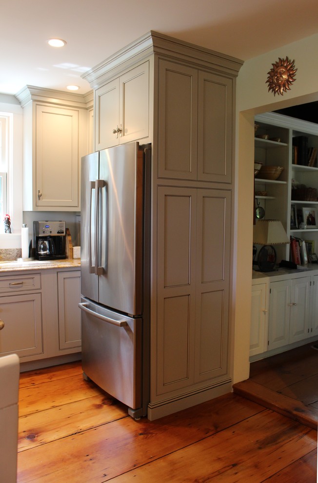 Inredning av ett lantligt kök och matrum, med en undermonterad diskho, granitbänkskiva, stänkskydd i glaskakel, rostfria vitvaror och ljust trägolv