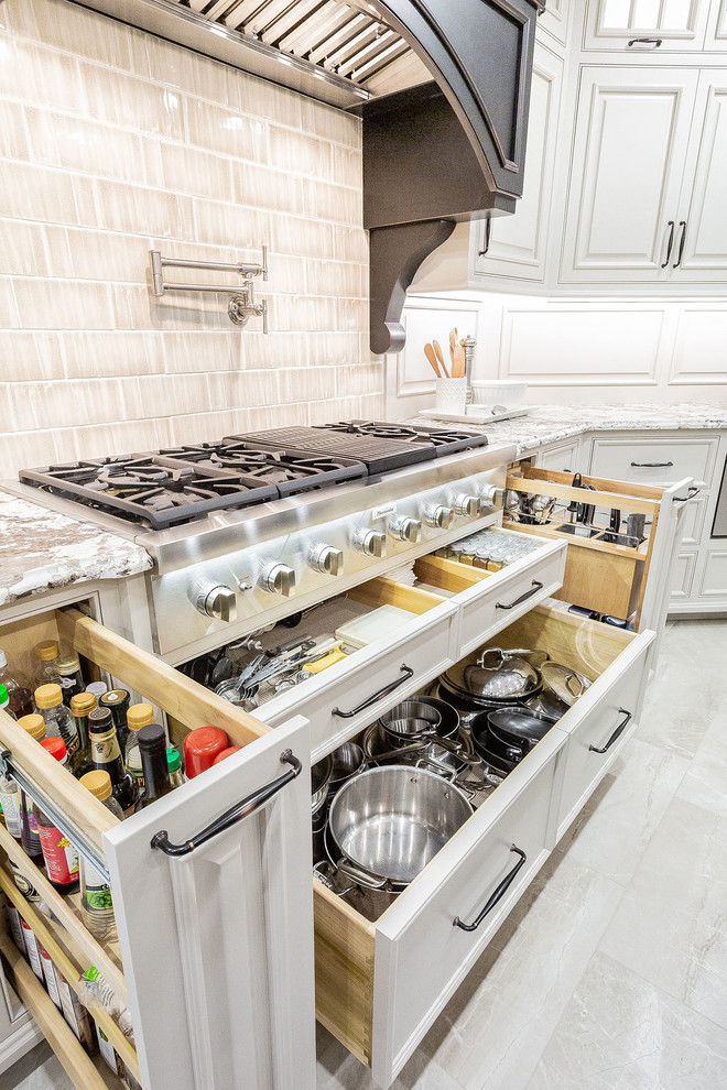 Example of a large transitional porcelain tile and beige floor kitchen design in Other with a farmhouse sink, beaded inset cabinets, gray cabinets, granite countertops, porcelain backsplash, stainless steel appliances, an island and beige countertops
