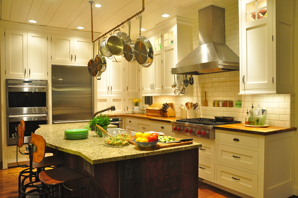 Bild på ett mellanstort lantligt parallellkök, med rostfria vitvaror, en rustik diskho, skåp i shakerstil, vita skåp, träbänkskiva, vitt stänkskydd, stänkskydd i keramik, mellanmörkt trägolv och en köksö