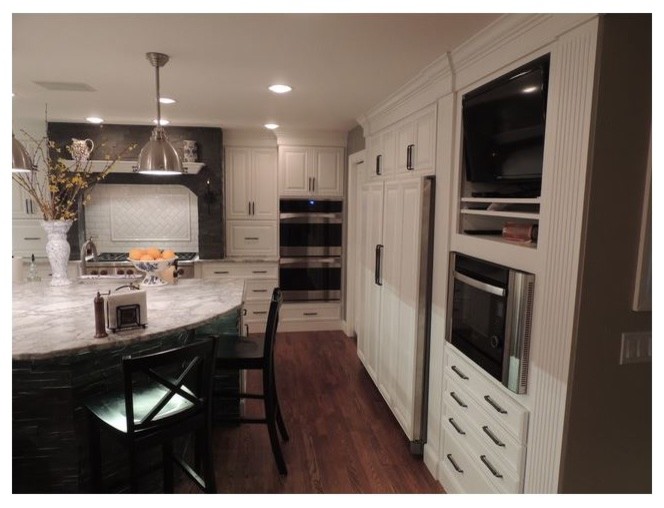 Inspiration för ett mellanstort vintage grå grått kök, med en nedsänkt diskho, luckor med upphöjd panel, vita skåp, granitbänkskiva, vitt stänkskydd, stänkskydd i glaskakel, svarta vitvaror, mellanmörkt trägolv, en köksö och brunt golv