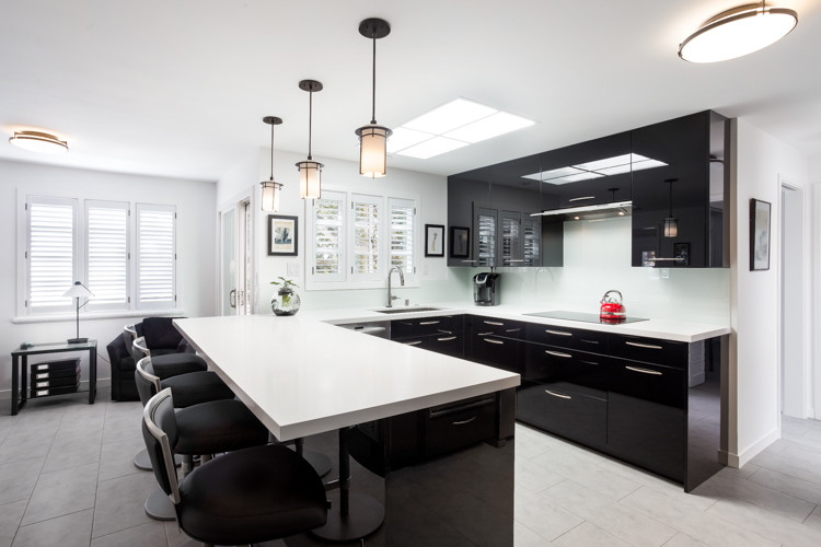 Contemporary u-shaped kitchen in San Francisco with a submerged sink, flat-panel cabinets, black cabinets, white splashback, glass sheet splashback, stainless steel appliances and a breakfast bar.