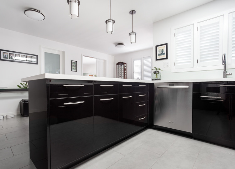 Bild på ett funkis u-kök, med en undermonterad diskho, släta luckor, svarta skåp, vitt stänkskydd, glaspanel som stänkskydd, rostfria vitvaror och en halv köksö