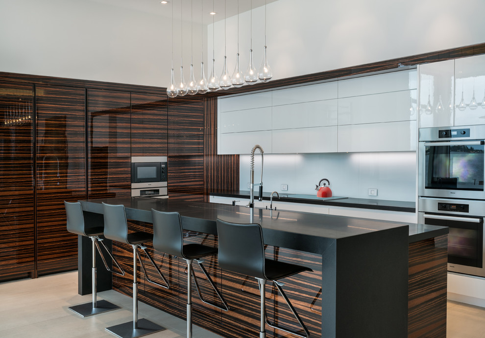 Trendy kitchen photo in Miami with flat-panel cabinets, white cabinets, white backsplash, stainless steel appliances and an island