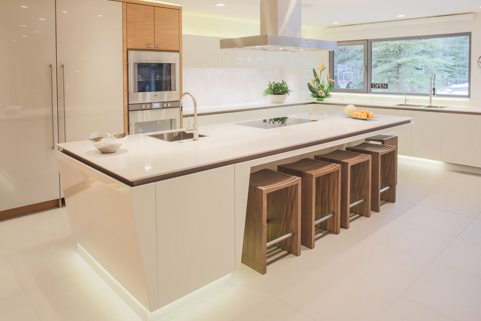 Inspiration for a large modern l-shaped open plan kitchen in Calgary with a double-bowl sink, flat-panel cabinets, white cabinets, composite countertops, white splashback, stone slab splashback, integrated appliances, ceramic flooring and an island.