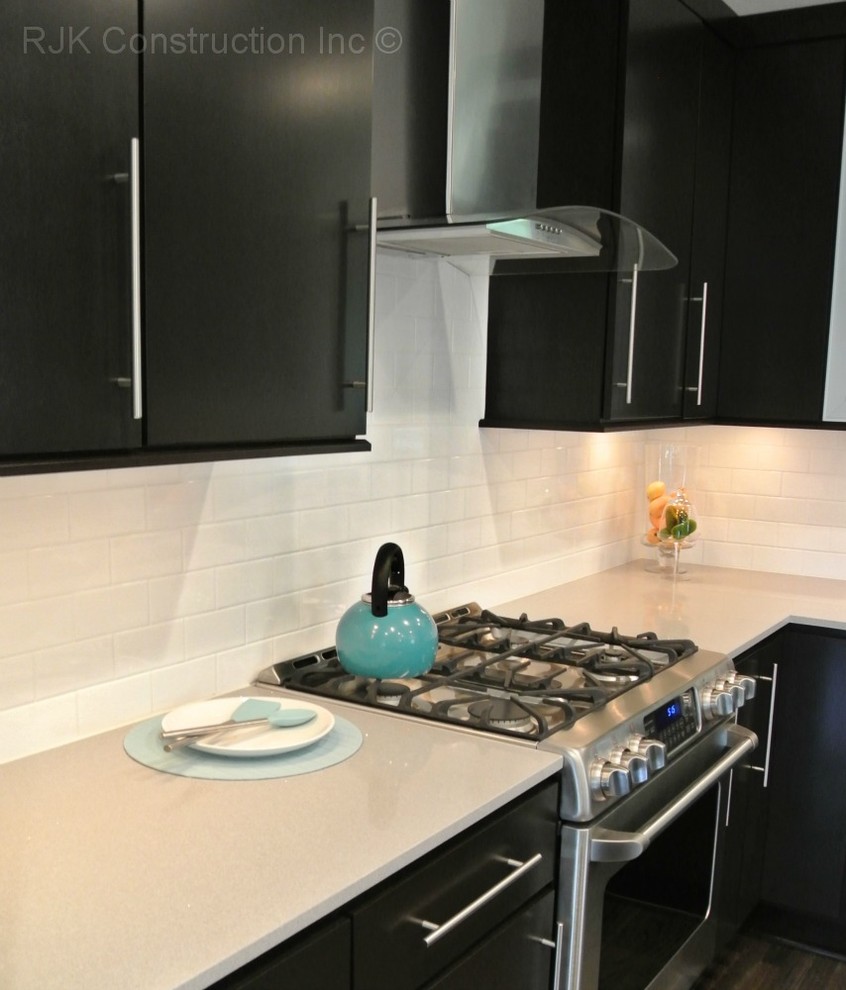 Cette image montre une cuisine américaine minimaliste en U avec un évier posé, une crédence blanche, une crédence en carrelage métro, un électroménager en acier inoxydable et parquet clair.
