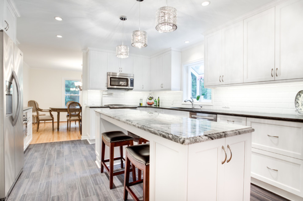 Example of a huge transitional u-shaped vinyl floor and gray floor enclosed kitchen design in Bridgeport with an undermount sink, recessed-panel cabinets, white cabinets, granite countertops, white backsplash, stainless steel appliances, an island and gray countertops
