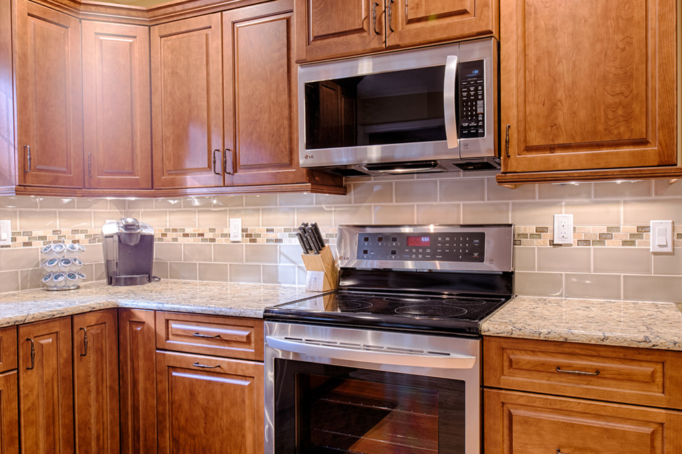 Exempel på ett avskilt, mellanstort klassiskt u-kök, med luckor med upphöjd panel, rostfria vitvaror, ljust trägolv, en undermonterad diskho, skåp i mellenmörkt trä, granitbänkskiva, grått stänkskydd, stänkskydd i tunnelbanekakel och beiget golv