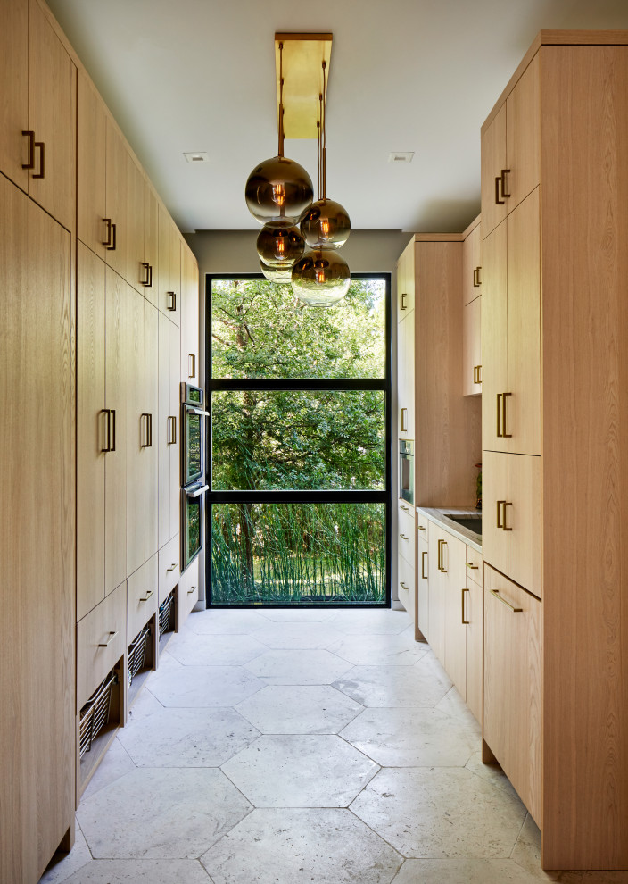 Ejemplo de cocina actual con armarios con paneles lisos, puertas de armario de madera clara y suelo gris
