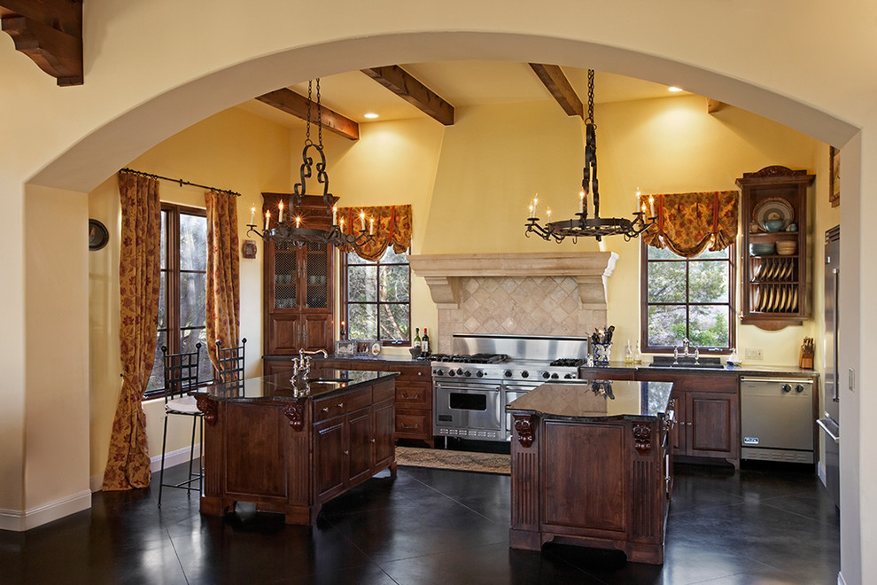 Inspiration for a mediterranean kitchen in Austin with raised-panel cabinets, dark wood cabinets and stainless steel appliances.