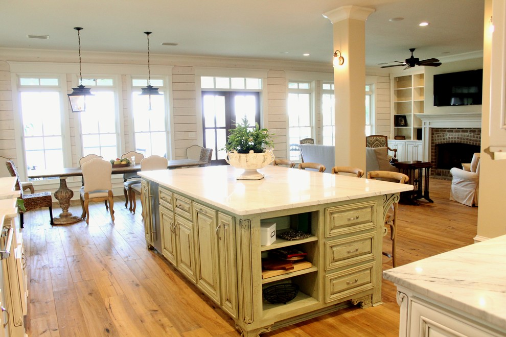 Eat-in kitchen - u-shaped light wood floor eat-in kitchen idea in Other with a farmhouse sink, raised-panel cabinets, white cabinets, marble countertops, white backsplash, porcelain backsplash, stainless steel appliances and an island
