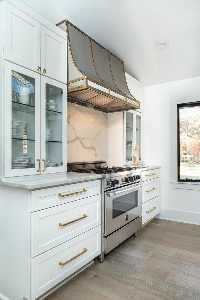 Kitchen - large transitional l-shaped light wood floor and brown floor kitchen idea in Chicago with an undermount sink, shaker cabinets, white cabinets, quartz countertops, gray backsplash, marble backsplash, stainless steel appliances and an island