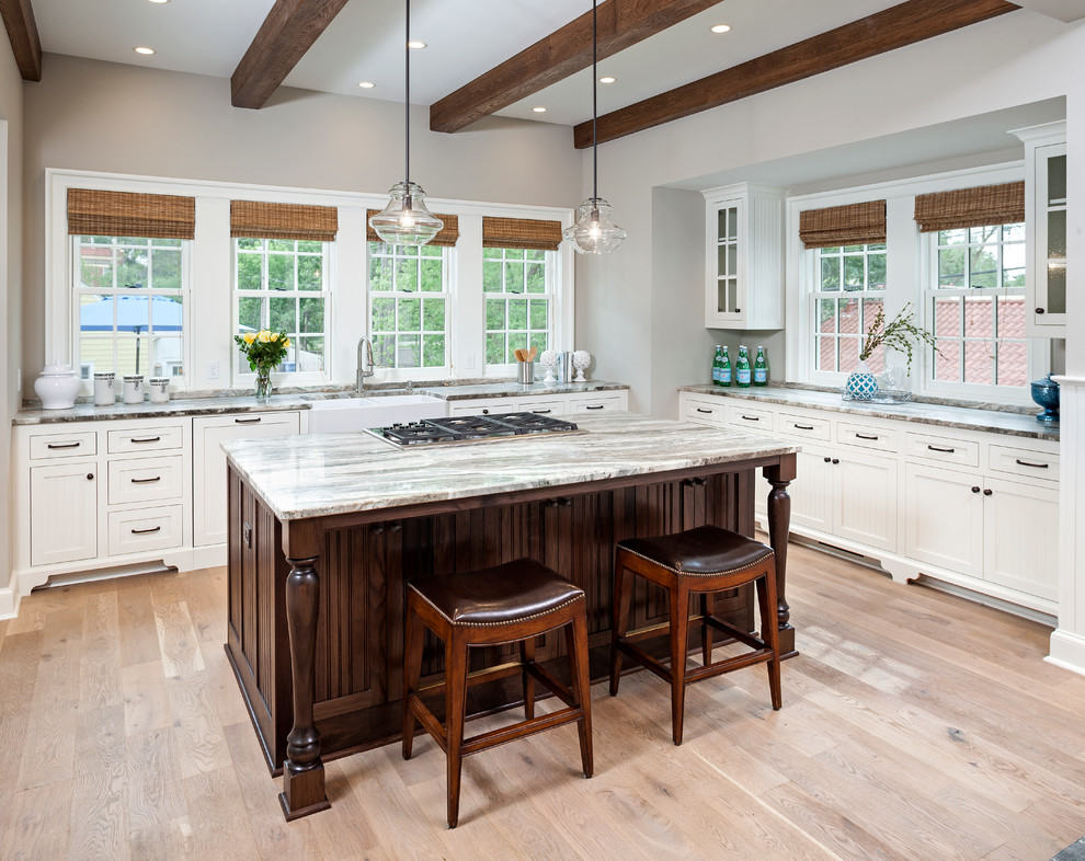 Example of a large beach style u-shaped light wood floor eat-in kitchen design in Minneapolis with a farmhouse sink, beaded inset cabinets, white cabinets, marble countertops and an island