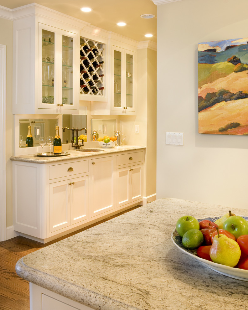 Elegant single-wall kitchen photo in San Francisco with an undermount sink, recessed-panel cabinets, white cabinets, granite countertops, metallic backsplash and mirror backsplash
