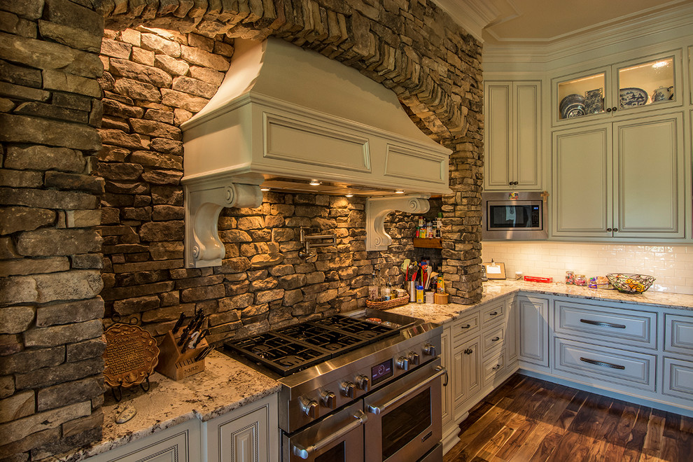 Large mountain style u-shaped medium tone wood floor and brown floor eat-in kitchen photo in Other with an undermount sink, raised-panel cabinets, distressed cabinets, granite countertops, brown backsplash, stone tile backsplash, stainless steel appliances, two islands and multicolored countertops