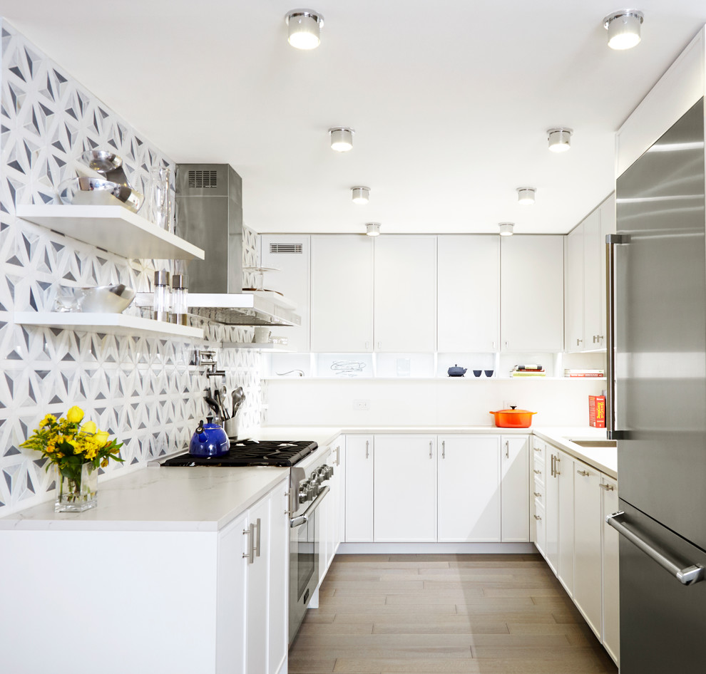 Small trendy u-shaped light wood floor open concept kitchen photo in New York with an undermount sink, white cabinets, quartz countertops, multicolored backsplash, stainless steel appliances, an island, recessed-panel cabinets and marble backsplash
